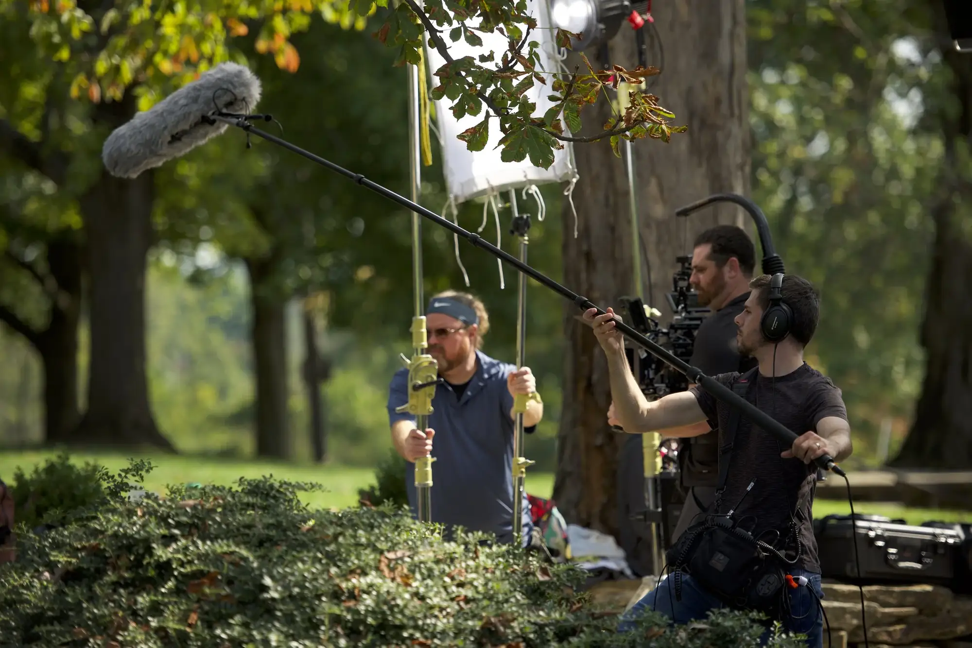 Boom operator and camera operator filming an actor in a park