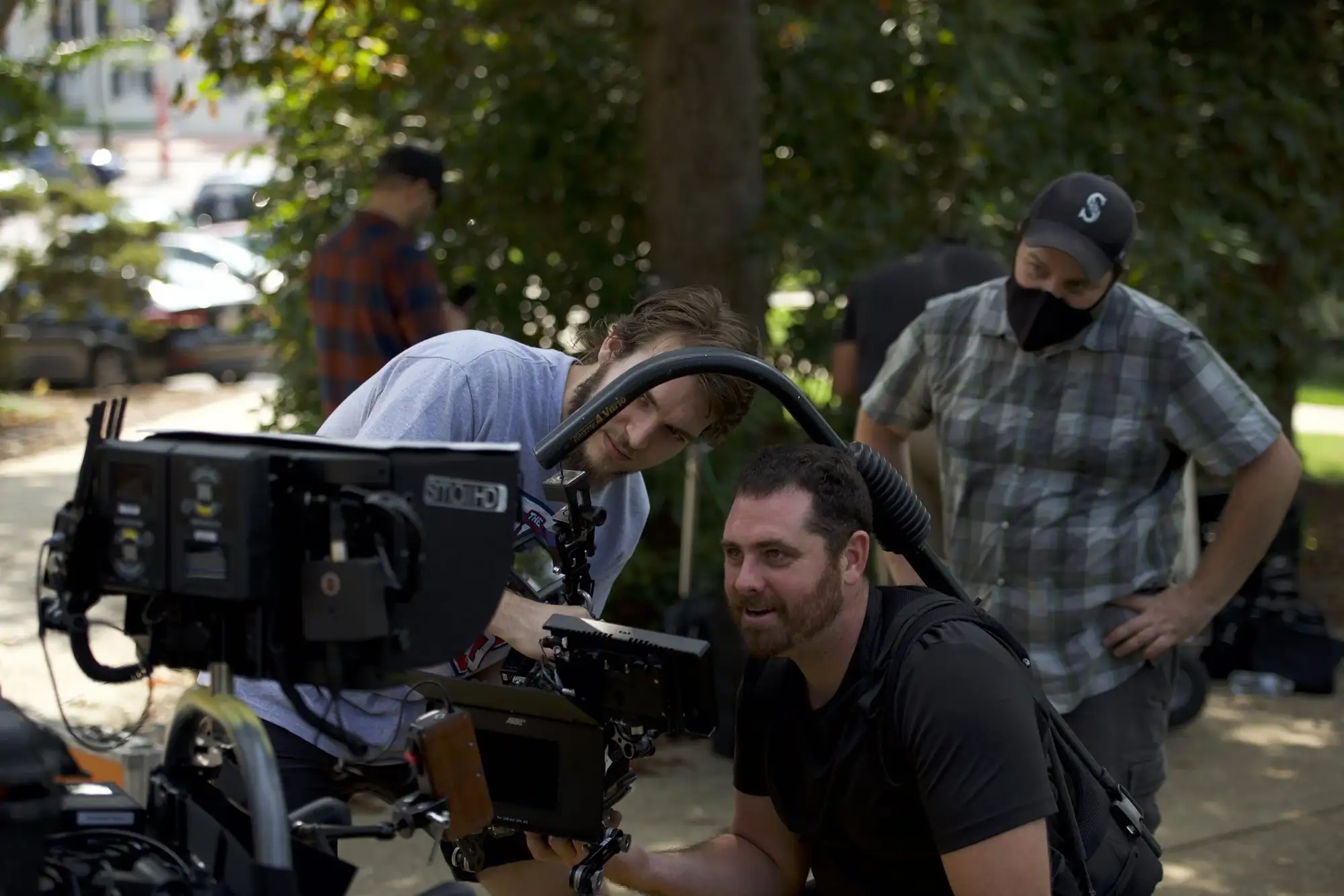 Crew gathered around a camera monitor during an outdoor shoot