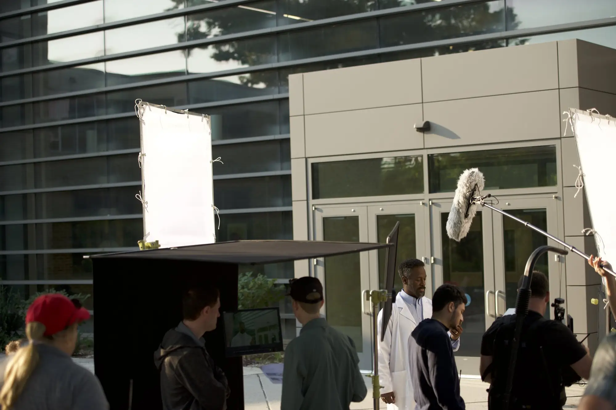 Crew filming a scene outside a glass office building