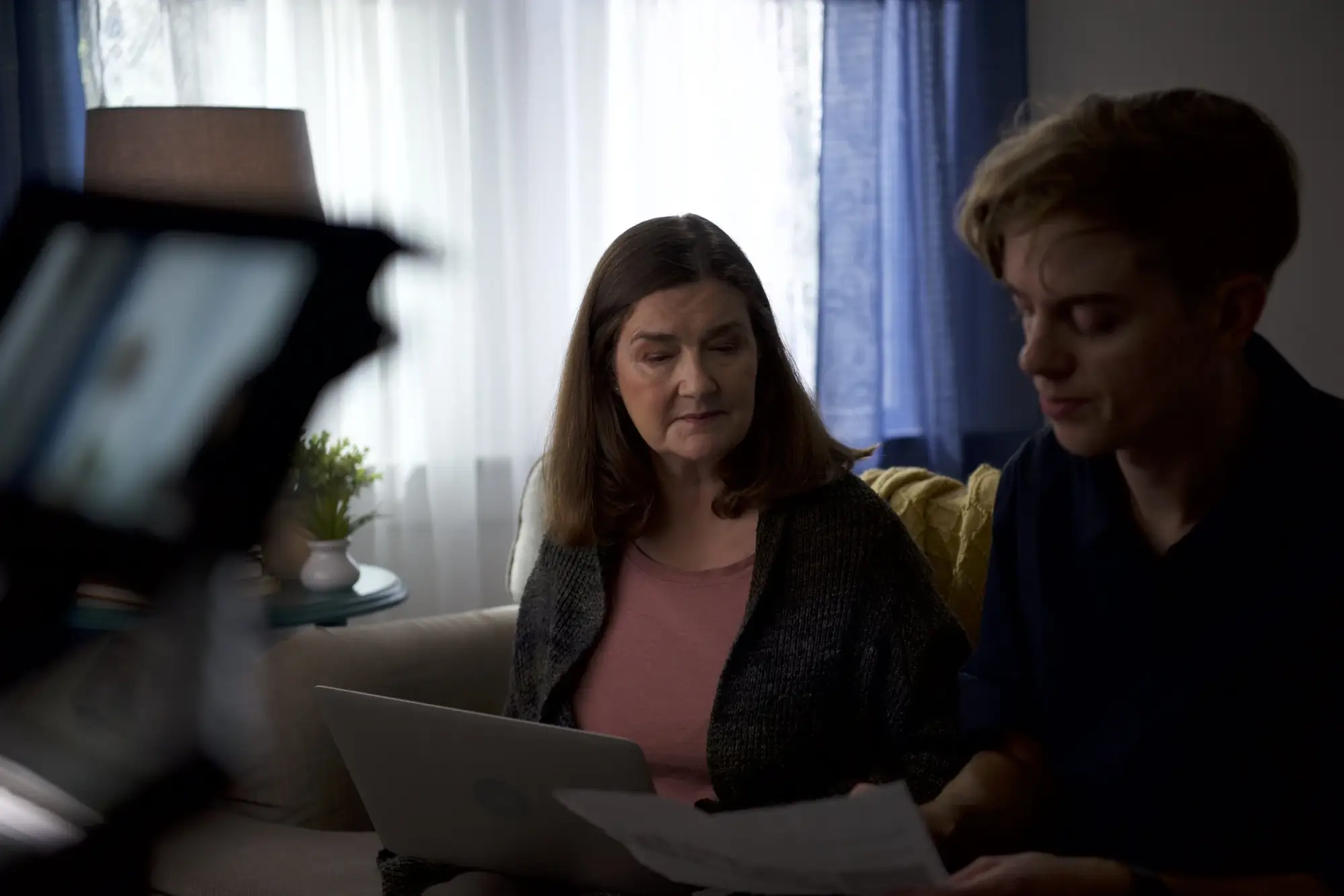 Actors reading papers on a couch during a scene
