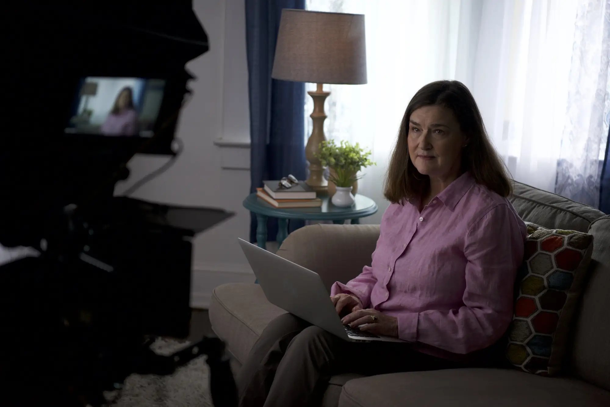 Camera framing an actor with a laptop on a living room couch