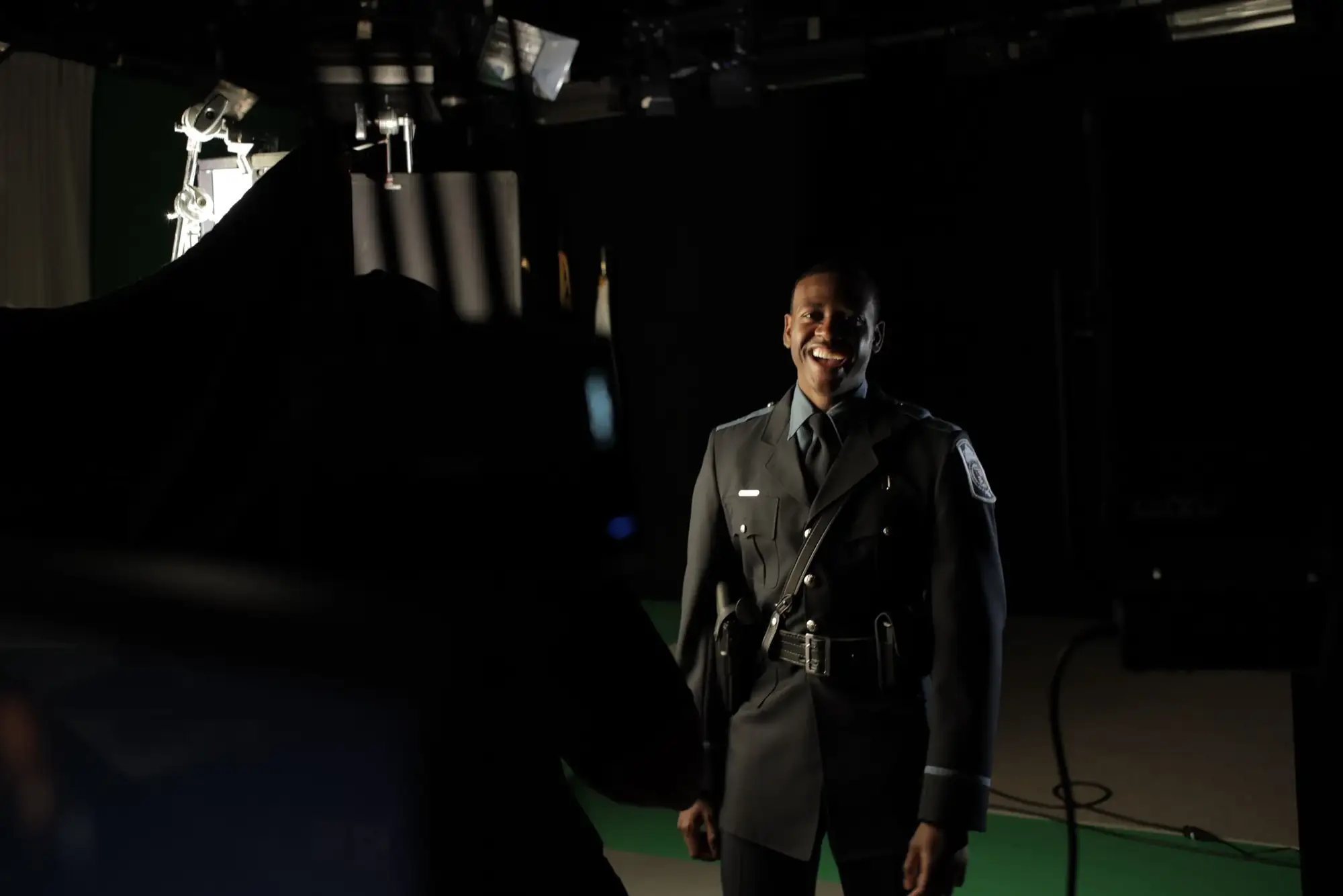 Smiling officer on a black studio set during a recruitment shoot
