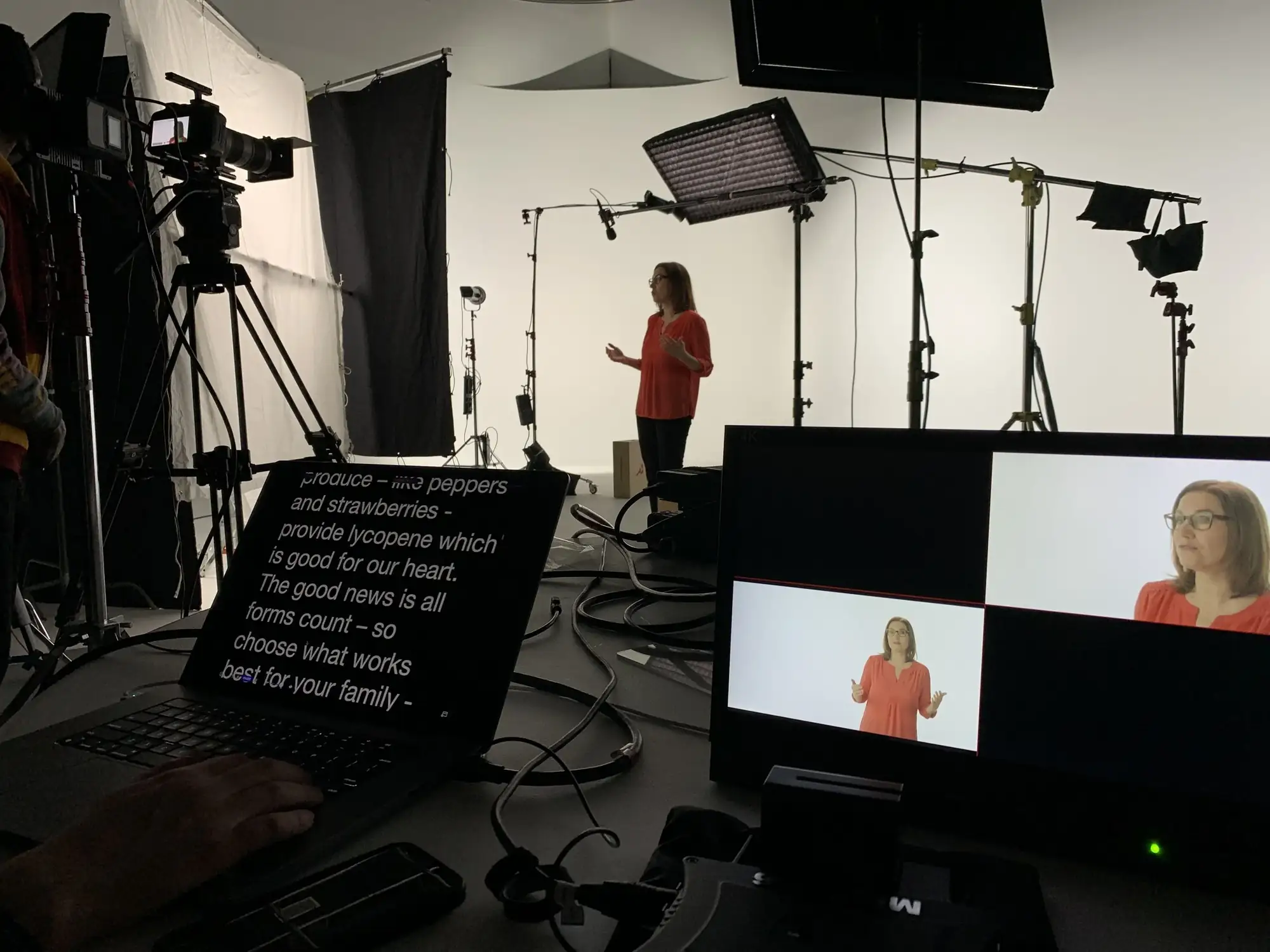 Woman filmed in studio with lighting rig, teleprompter and monitors