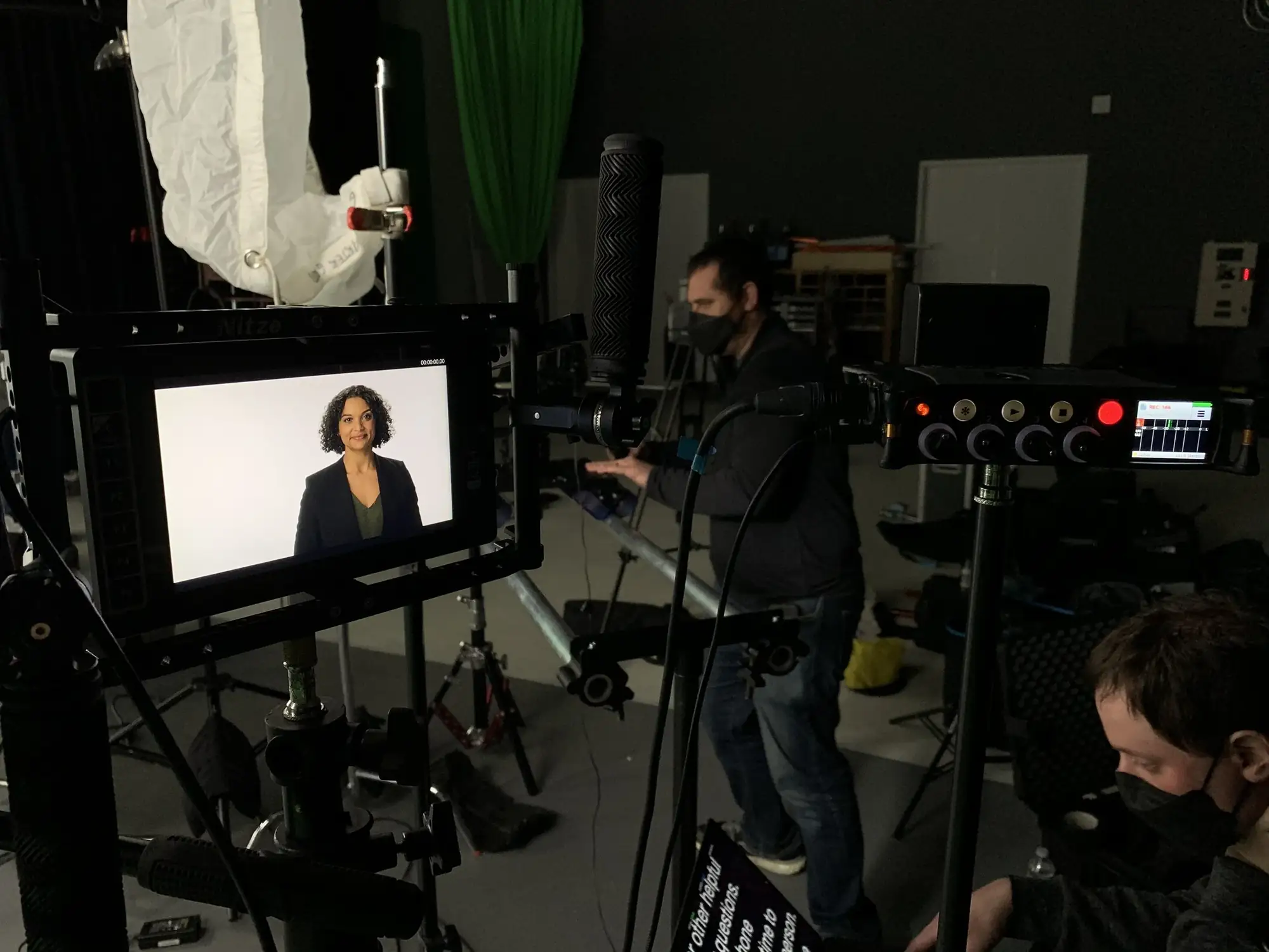 Camera crew with a monitor showing a woman being interviewed