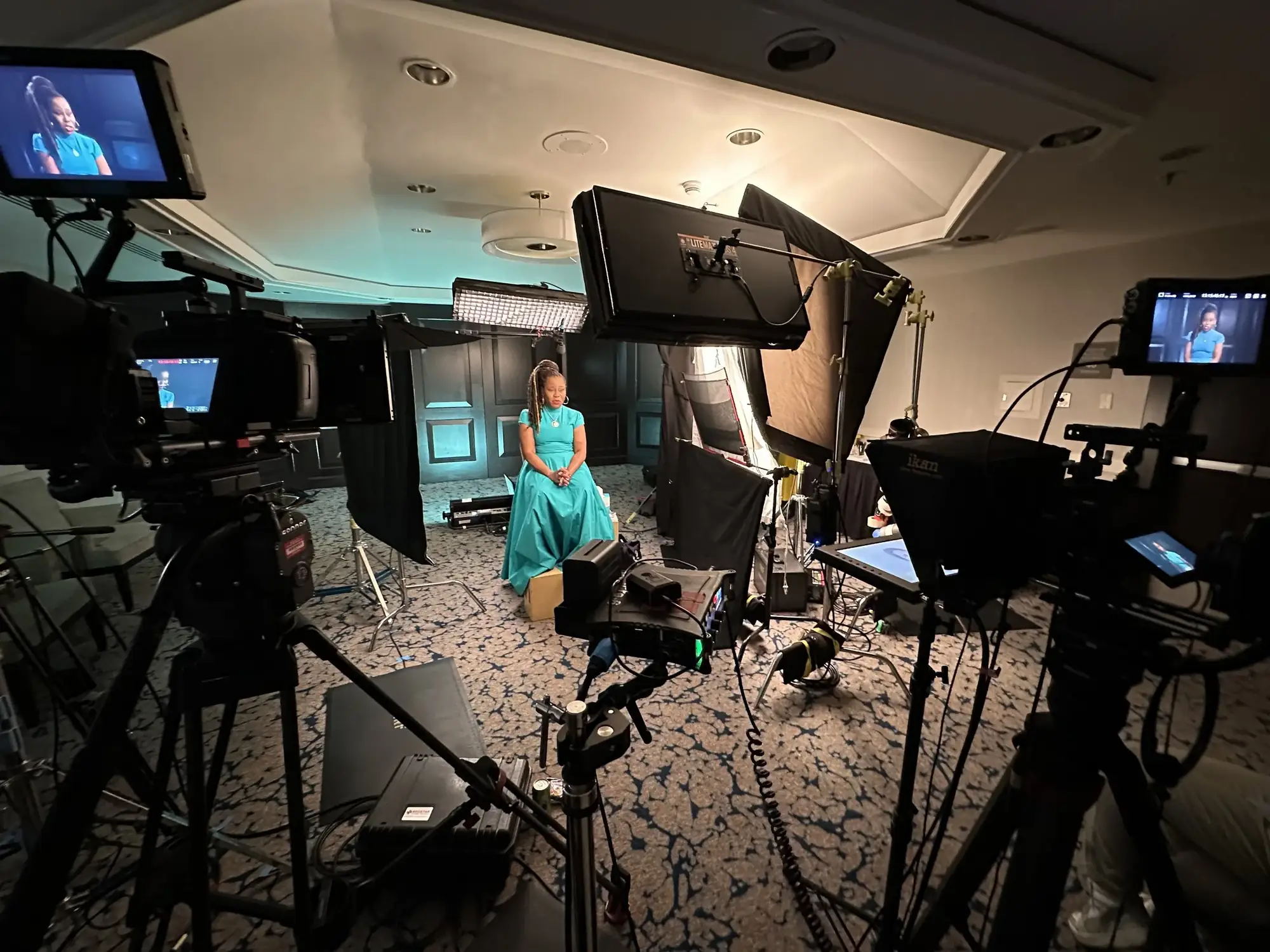 Multi-camera interview setup with a woman seated in a hotel ballroom