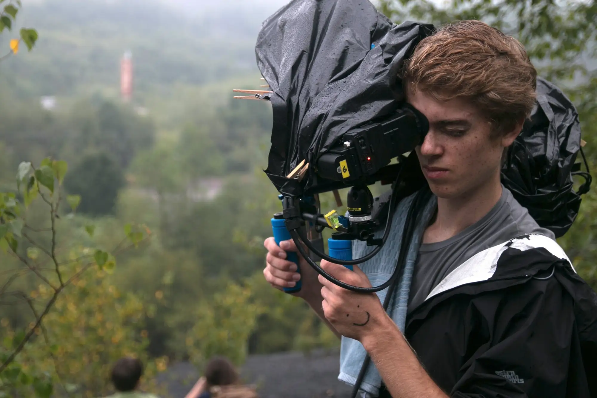 Camera operator filming from a foggy hillside