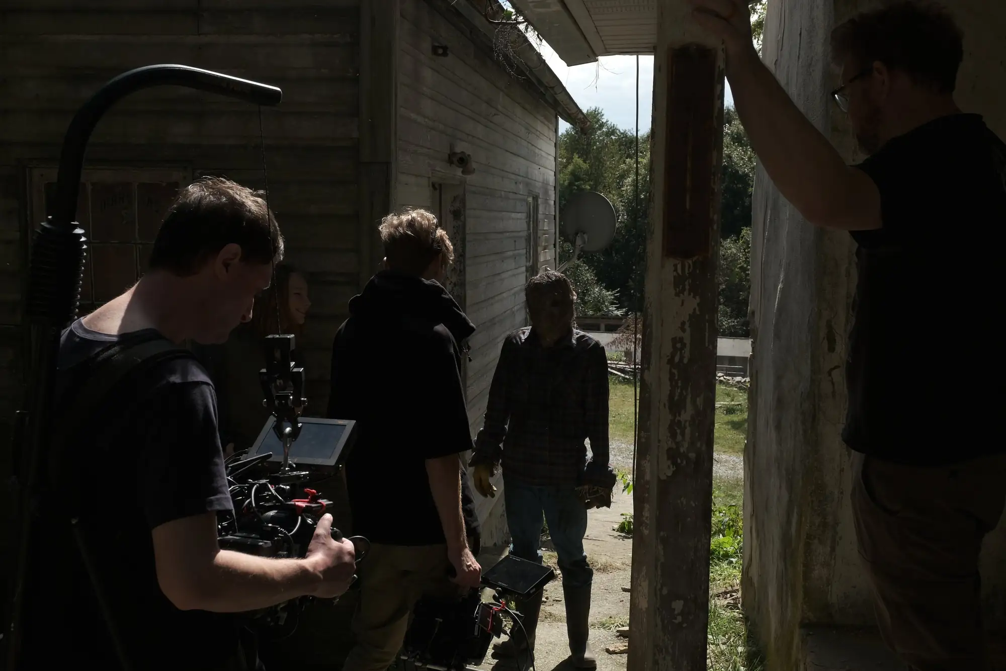 Crew filming outside a weathered wooden cabin