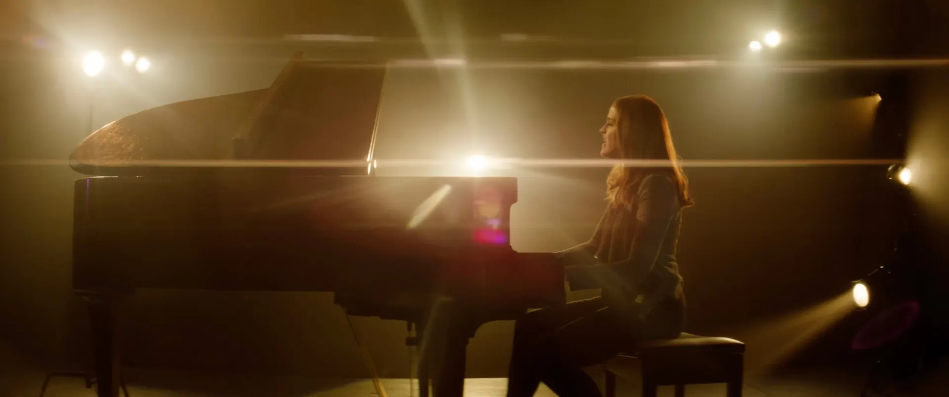 Anamorphic film frame from Ghost Light — singer at a grand piano in haze